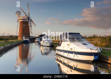 Des bateaux amarrés près de Horsey Windpump sur le parc national Broads à Norfolk, Royaume-Uni, au lever du soleil Banque D'Images