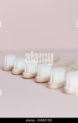 Un super gros plan de quelques brosses à dents en bambou sur un fond rose clair Banque D'Images