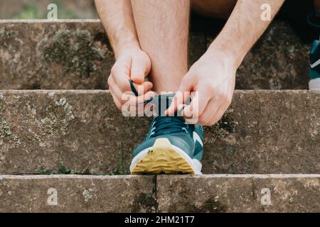 Un super gros plan d'un homme attachant les lacets sur ces chaussures de sport sur le béton avant de s'entraîner à la forme physique Banque D'Images