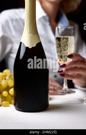 une bouteille de champagne sur fond blanc et en arrière-plan une fille avec un verre Banque D'Images