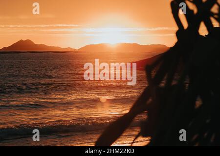 Un feu de joie sur la plage lors d'un coucher de soleil massif et coloré Banque D'Images