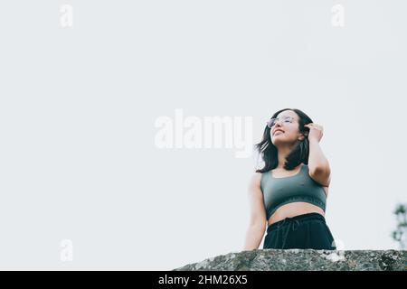 Jeune fille arabe dans un balcon sur des vêtements de sport pendant une journée ensoleillée, souriant et regardant loin de l'appareil photo avec l'espace de copie, image à l'envers Banque D'Images