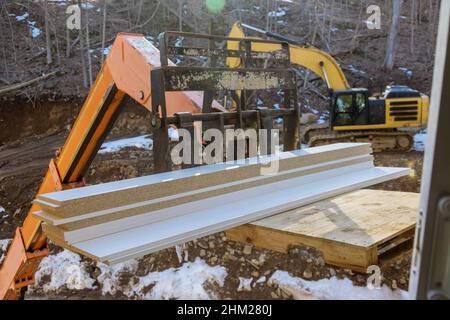 Étagères en bois soulevées par un chariot élévateur à flèche dans les matériaux de construction avec le chantier de construction Banque D'Images