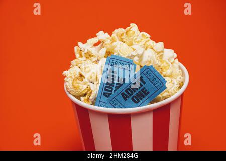 Pop-corn avec film cinématographique dans une boîte ronde et autour sur fond rouge vif. Banque D'Images