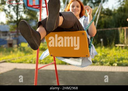 La fille se balance sur un marais.Adolescent sur l'aire de jeux.Balançoire à corde en été. Banque D'Images