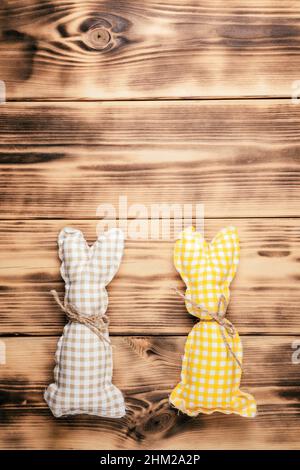Carte postale de Pâques pour les fêtes, deux lapins carrés de couleur marron, blanche et jaune faits à la main avec foulard sur bois naturel Banque D'Images