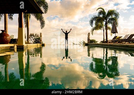 Un homme debout au bord de la piscine à débordement Banque D'Images