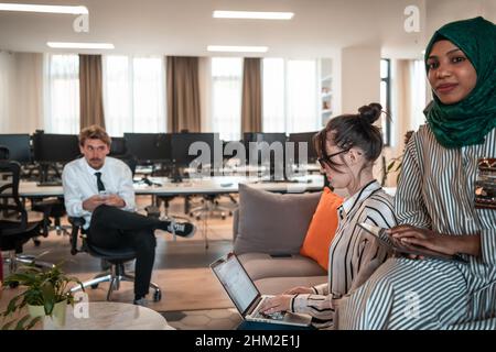 Équipe d'affaires multiethnique de démarrage ayant des brainstorming dans l'espace de détente de l'intérieur de bureau moderne travaillant sur ordinateur portable et tablette Banque D'Images