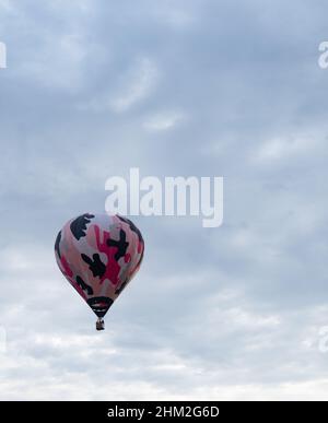 Montgolfière à camouflage rose en vol avec pilote féminin et passagers dans un panier en osier dans le Big Sky International Balloon Rendezvous à Billi Banque D'Images