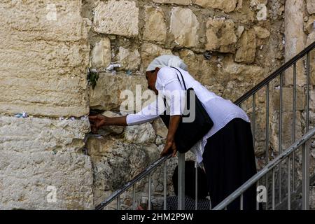 Une femme atteint pour placer une prière dans un étau du mur occidental, ou mur des lamentations, au Mont du Temple à Jérusalem, en Israël. Banque D'Images