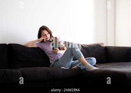 Une femme ennuyée utilise son téléphone le matin Banque D'Images