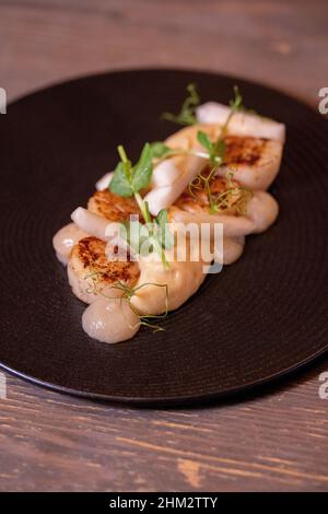 Noix de Saint-Jacques Hokkaido grillées, purée de panais, condiment de yuzu et de poire, servies avec un verre de vin Banque D'Images