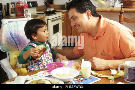 Austin Texas USA, 1995: Un père hispanique supervise le petit déjeuner pour sa fille philippine-américaine de deux ans.M. EC-0046 ©Bob Daemmrich Banque D'Images