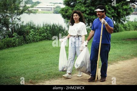 Austin Texas USA: Les bénévoles transportant des sacs à ordures ramassent les déchets dans le parc de la ville pendant la journée de nettoyage à l'échelle de la communauté.©Bob Daemmrich Banque D'Images