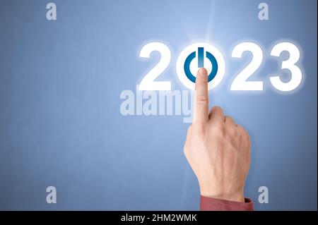 Doigt appuyant sur le bouton bleu START 2023 de l'interface virtuelle en arrière-plan avec un espace de copie pour le texte.Concept de couverture Business Happy New Year 2023.Beginn Banque D'Images