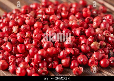 Les grains de poivre rouge sont éparpillés sur fond de bois vintage Banque D'Images