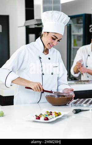 latino femme pâtissière portant l'uniforme tenant un bol préparant de délicieux chocolats sucreries à la cuisine au Mexique Amérique latine Banque D'Images