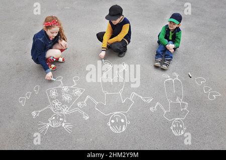 Les enfants bronzer sur l'asphalte dans le parc de printemps. Banque D'Images