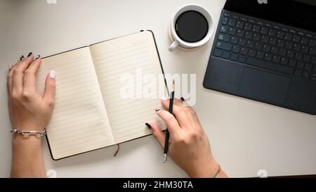 Une femme écrit un livre dans un espace de travail moderne.Femme d'affaires travaillant sur le bureau. Vue sur le dessus Banque D'Images