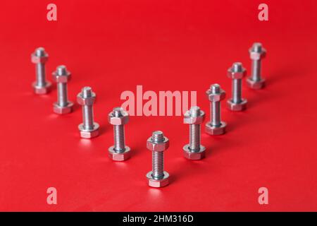 Boulons et écrous en acier isolés sur fond rouge Banque D'Images
