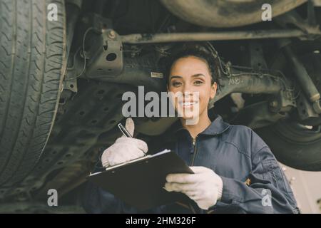 concept de contrôle de train de roulement de voiture en bon état, femme mécanicien liste de travail garage de voiture. Banque D'Images