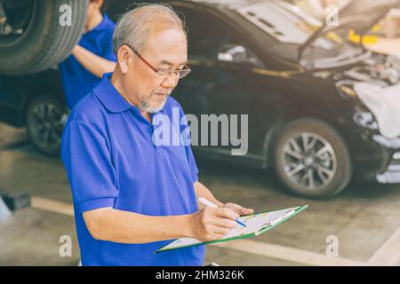 Asiatique professionnel adulte propriétaire de garage travaillant la vérification de la voiture de client Banque D'Images