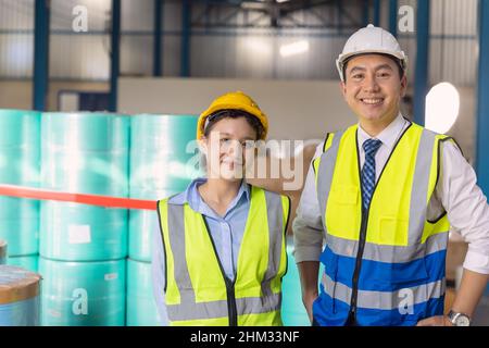 Jeune ingénieur travaillant femme debout avec un homme adulte travailleur avec un casque de sécurité en arrière-plan de l'usine Banque D'Images