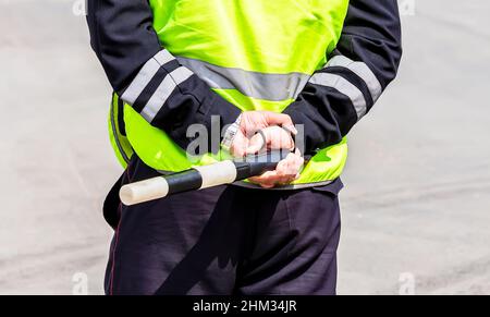 Bâton de police de la circulation, avec bouton de contre-jour et sangle dans les mains d'un agent de police.Bâton de la réglementation de la circulation Banque D'Images