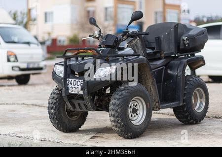 Side, Turquie - 25 janvier 2022 : le quad noir est garé dans la rue par une chaude journée d'été contre le parking Banque D'Images