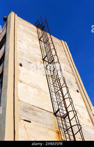 Vieux escalier rouillé sur le mur de la construction d'une usine abandonnée.La crise, la chute de l'économie, l'arrêt de la capacité de production a conduit à Banque D'Images