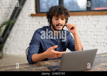 Concept de travail, de technologie et de personnel à distance.Un homme souriant avec un casque et un ordinateur portable pour la visioconférence au bureau à domicile.Homme d'affaires en casque client de conseil Banque D'Images