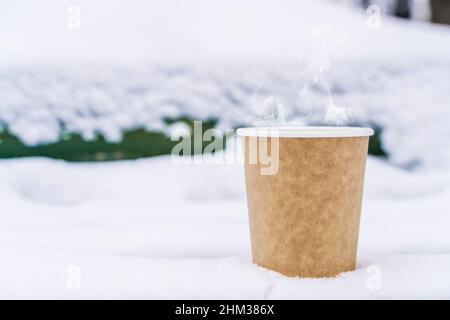 Café dans une tasse de papier sur fond enneigé d'hiver.Boisson chaude par temps froid.Photo de haute qualité Banque D'Images