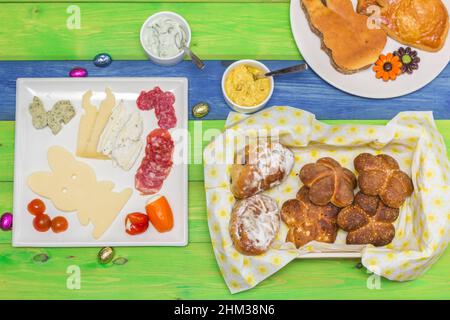 Brunch de Pâques avec pain, viande, fromage et salade sur une table en bois colorée Banque D'Images