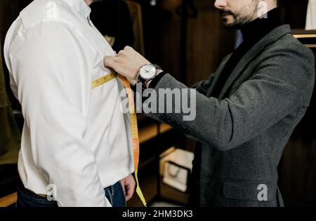 un ancien modèle sur mesure prenant des mesures de poignet du client dans un petit atelier d'atelier Banque D'Images
