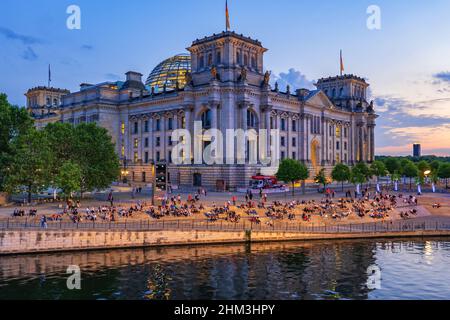 Berlin, Allemagne - 4 août 2021 : bâtiment Reichstag à la tombée de la nuit et personnes dans les escaliers au bord de la rivière Spree, point de repère de la ville. Banque D'Images