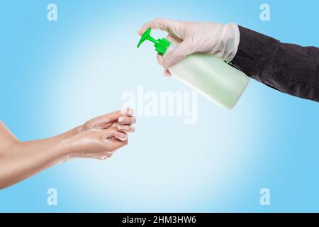 Lavage des mains.Un homme en gants médicaux presse le savon liquide sur les mains d'une femme qui les lave avec de la mousse.mains gros-up.fond bleu.concept de Banque D'Images