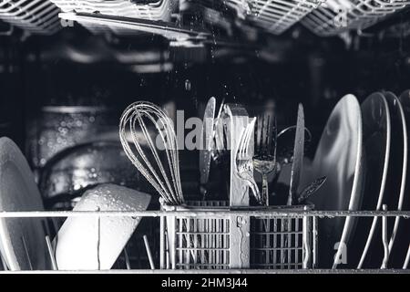 Vue avant de l'ouverture automatique en acier inoxydable intégré entièrement intégré contrôle supérieur lave-vaisselle gamme machine avec ustensiles propres, couverts, verres, vaisselle, assiettes à l'intérieur dans la cuisine moderne maison Banque D'Images