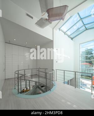 Intérieur moderne du hall dans une maison privée de luxe.Escalier en colimaçon en verre et en métal.armoire blanche. Banque D'Images