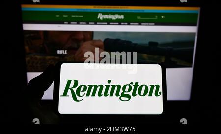 Personne tenant un smartphone avec le logo de la société américaine RemArms LLC (Remington Arms) à l'écran devant le site Web. Mise au point sur l'affichage du téléphone. Banque D'Images