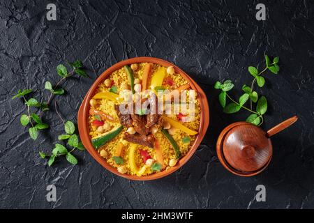 Couscous à la viande et aux légumes, plats marocains festifs, plan suspendu sur fond d'ardoise noire Banque D'Images