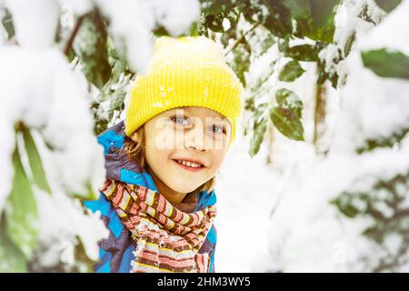 Un petit garçon aime l'extérieur sur la neige.Il joue cacher et chercher. Banque D'Images