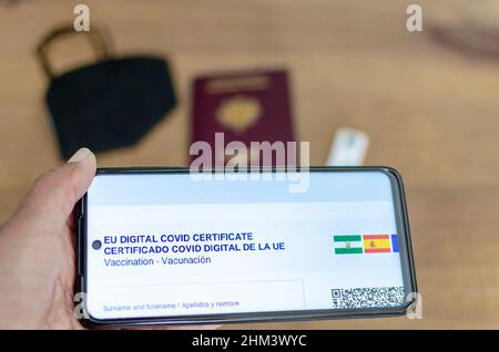 Accent sélectif sur un smartphone avec certificat numérique Covid. Passeport, test rapide d'antigène et masque FFP2 en arrière-plan. Nouvelle norme et co. De déplacement Banque D'Images