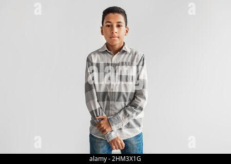 Petit garçon noir sérieux regardant l'appareil photo sur fond gris Banque D'Images