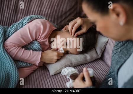 Mère prenant soin de sa fille malade à la maison. Banque D'Images