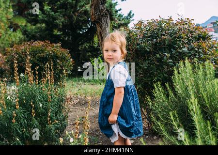 Petite fille marche dans le jardin parmi de belles plantes vertes du sud Banque D'Images