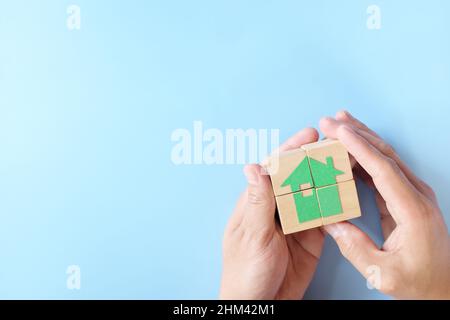 Puzzle d'icône maison en bois à la main humaine. Investissement immobilier, sécurité et concept de propriété. Banque D'Images