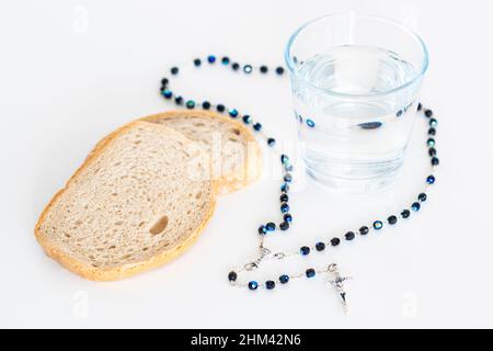 Rosary, pain et eau en verre sur table blanche, concept rapide Banque D'Images