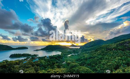 Vue panoramique de drone haute résolution sur la côte de l'île Mahé au coucher du soleil, avec ciel spectaculaire, nuages, forêt tropicale luxuriante et petites îles autour. Banque D'Images