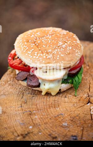 Délicieux hamburger sur une surface rustique en bois. Barbecue au feu de camp. Faible profondeur de champ Banque D'Images