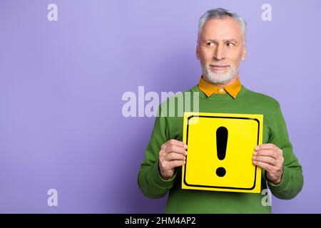 Photo de l'homme de rêve retraité vêtu d'un pull vert tenant une carte de danger vide espace isolé couleur violet fond Banque D'Images